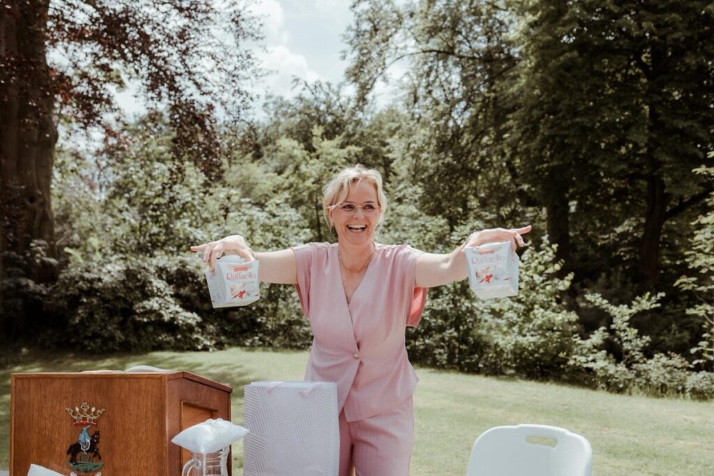 Trouwambtenaar Yvonne Dijkstra lacht met twee doosjes Raffaello tijdens de ceremonie