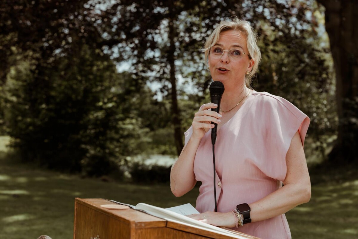Trouwambtenaar Yvonne Dijkstra spreekt het bruidspaar toe tijdens een trouwceremonie in het groen